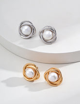 A close-up image of two pairs of pearl stud earrings displayed on the white stage.