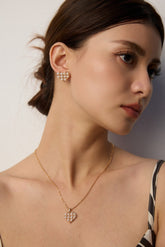 Woman wearing a gold necklace and earrings against a neutral background