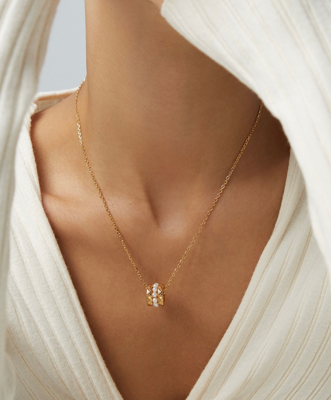 Gold necklace with a pendant on a person wearing a white garment