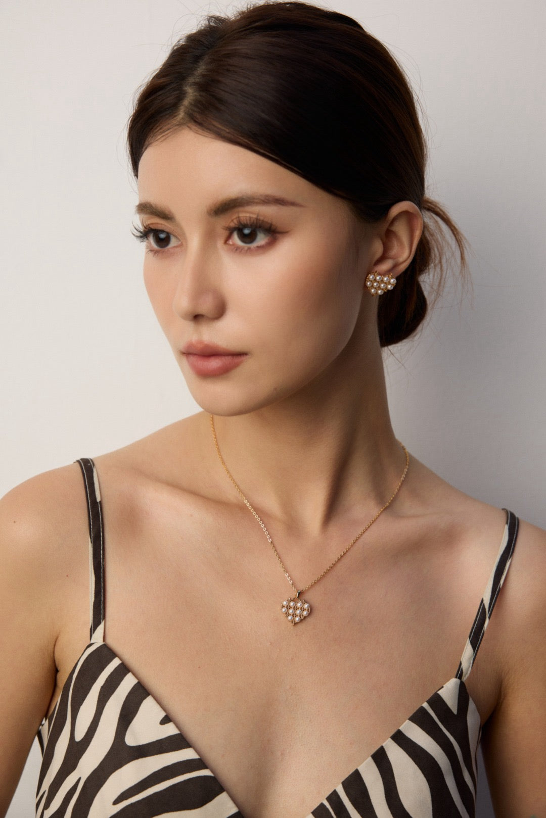 Woman wearing a zebra print dress with a gold necklace and earrings against a plain background