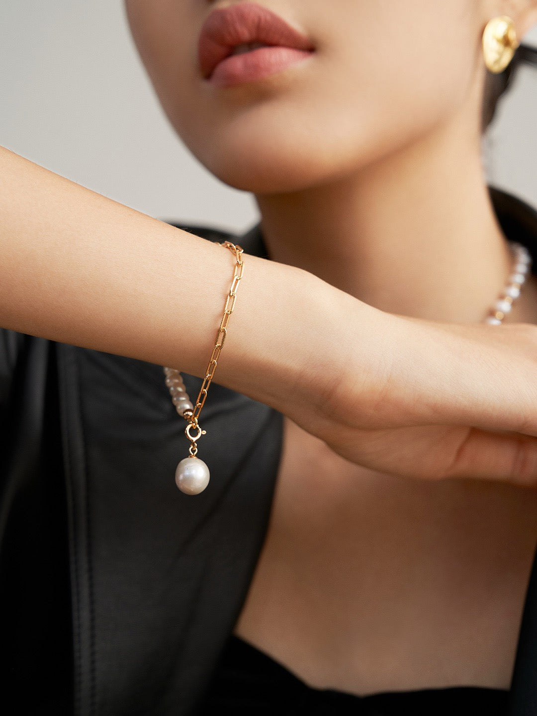 A close-up of the Luna Dual-Chain Freshwater Pearl Bracelet in gold, showcasing the 10.5mm pearl charm.
