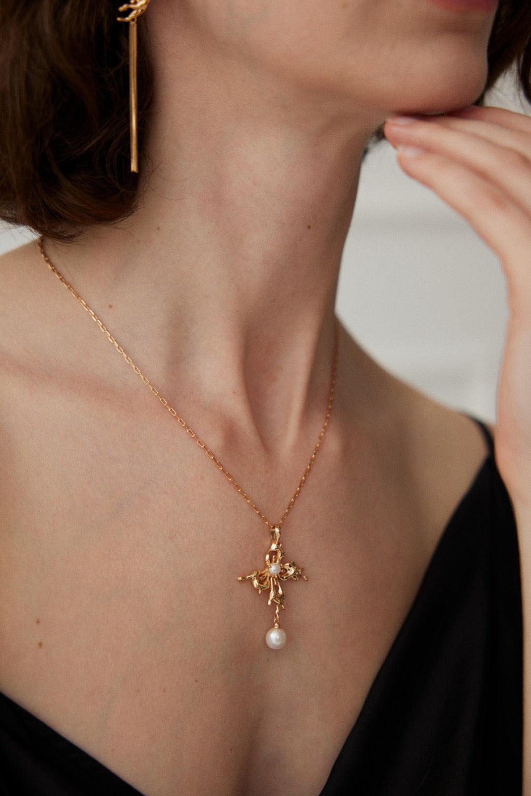 A side view of the model is wearing the Gold Pearl Pendant Necklace with the black deep v dress.