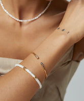 A person showing off a gold-colored bangle with white and gold zircon embellishments on their wrist.