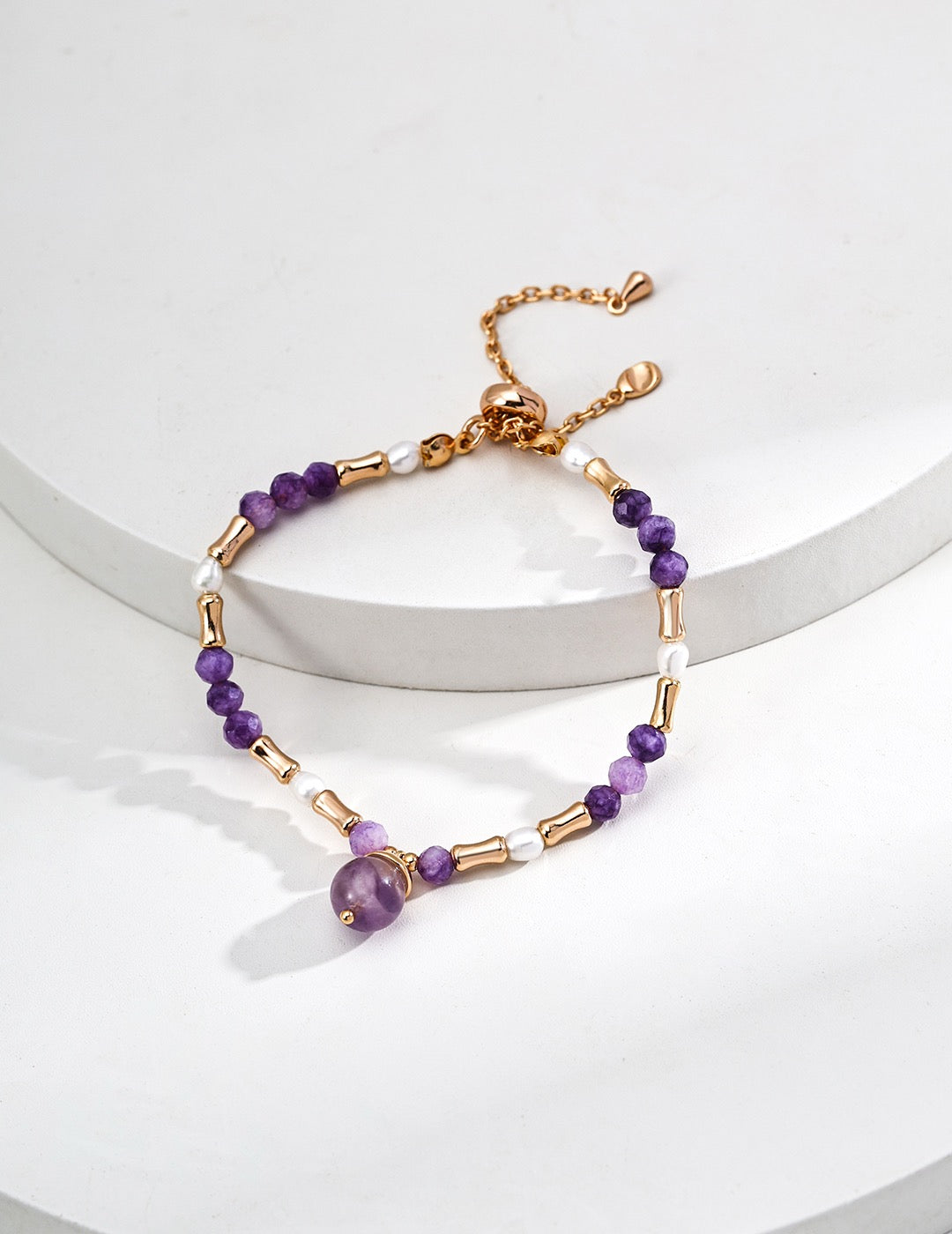 Bracelet with purple beads and gold accents on a white background