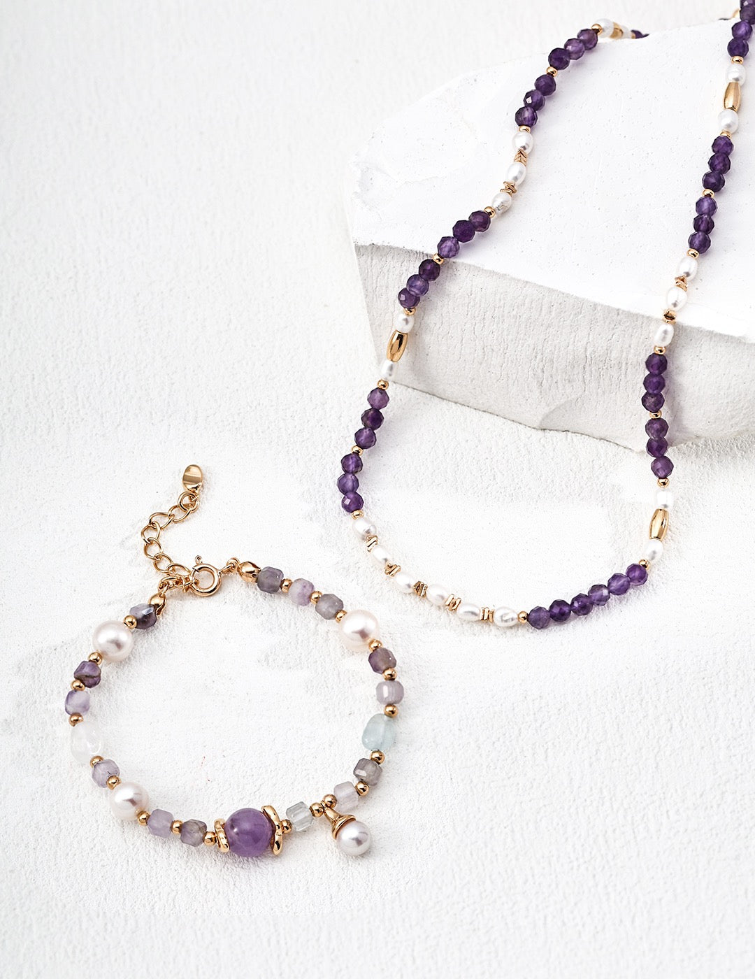 Beaded necklace with purple and gold beads on a white background