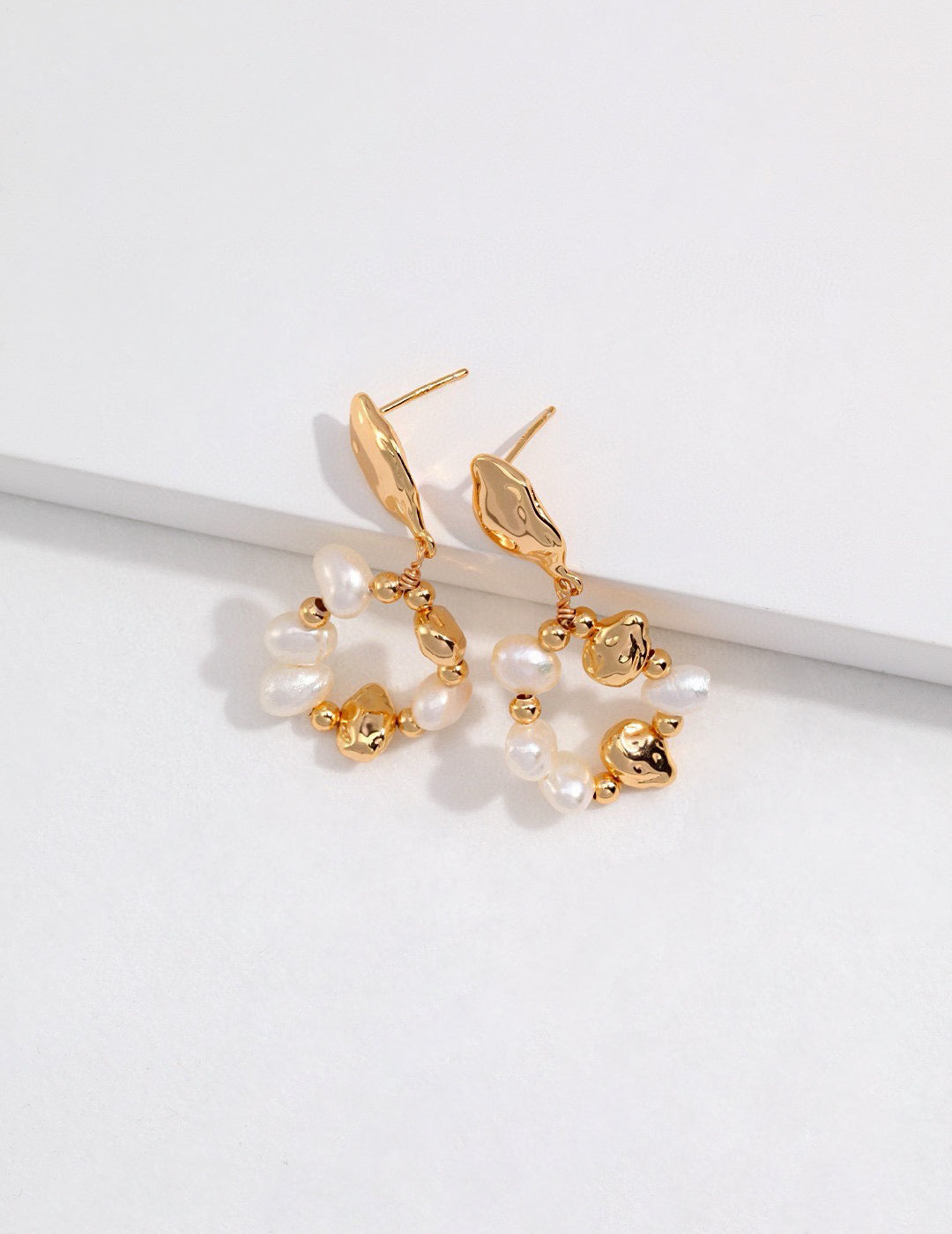 Gold and pearl earrings on a white background