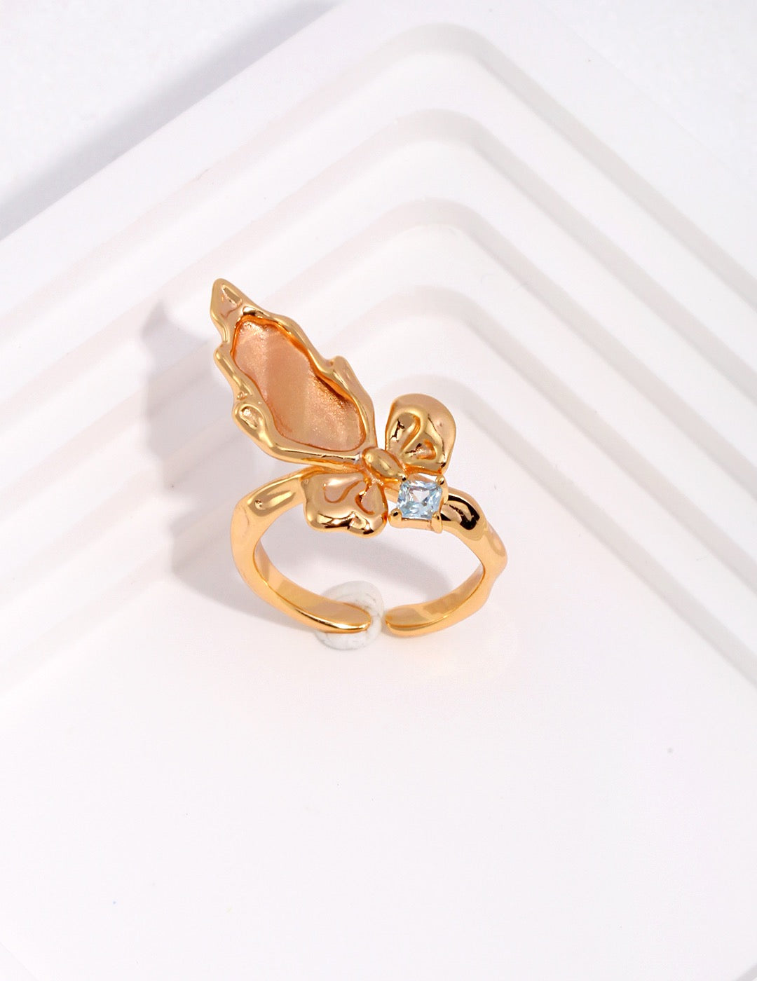 Gold butterfly ring with a small gemstone on a white background