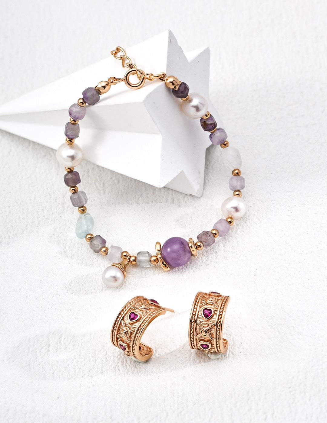 Bracelet and earrings set with purple and gold jewelry on a white background.