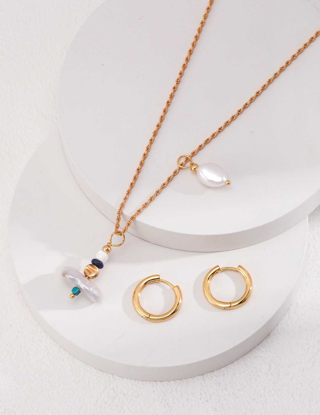 Gold necklace and earrings on a white surface. Detachable earrings into pendants.