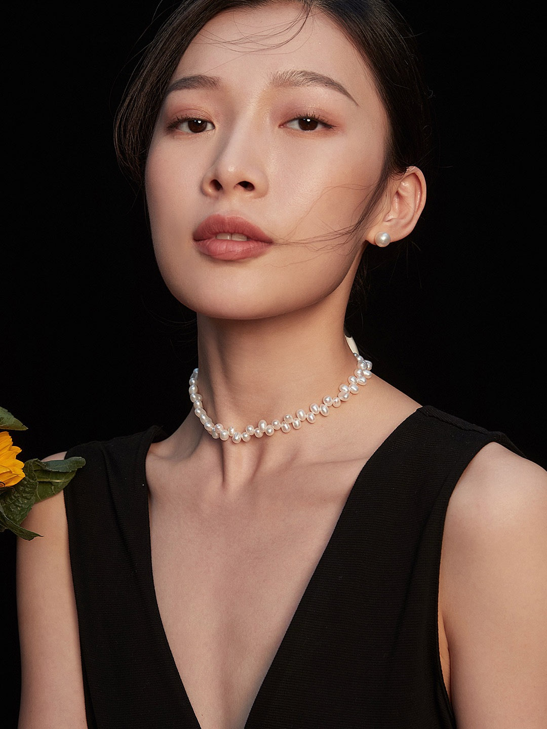 Woman wearing a pearl necklace against a black background