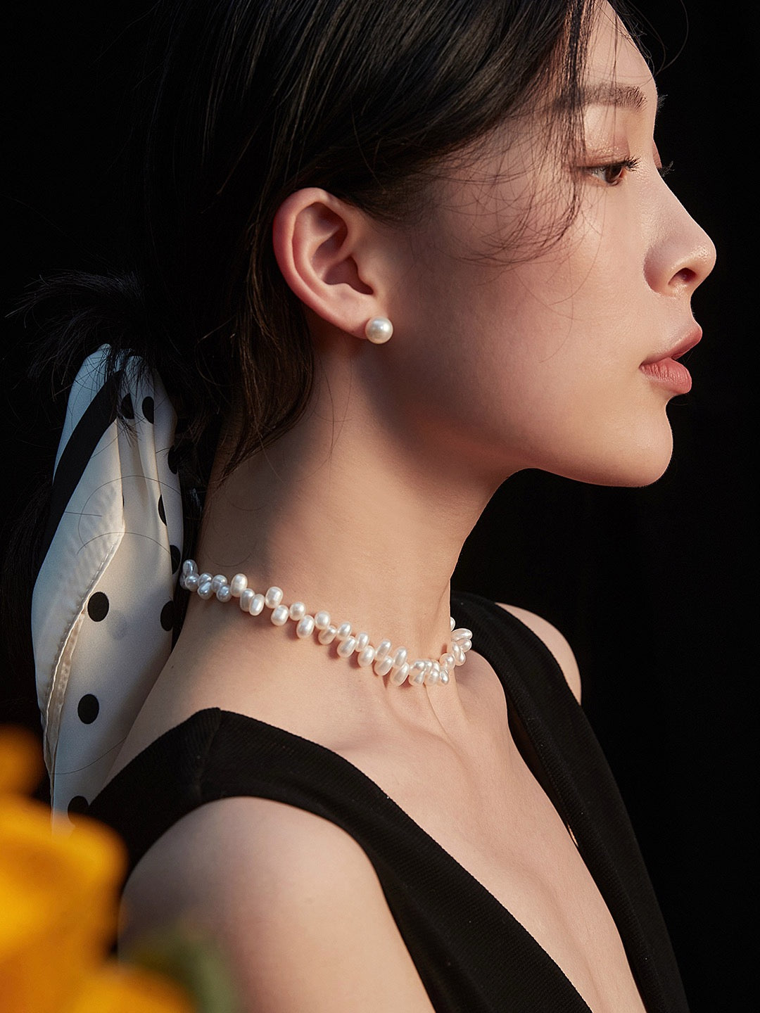 Woman wearing a pearl necklace with a black background