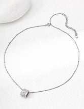 Silver necklace with a round pendant on a white background