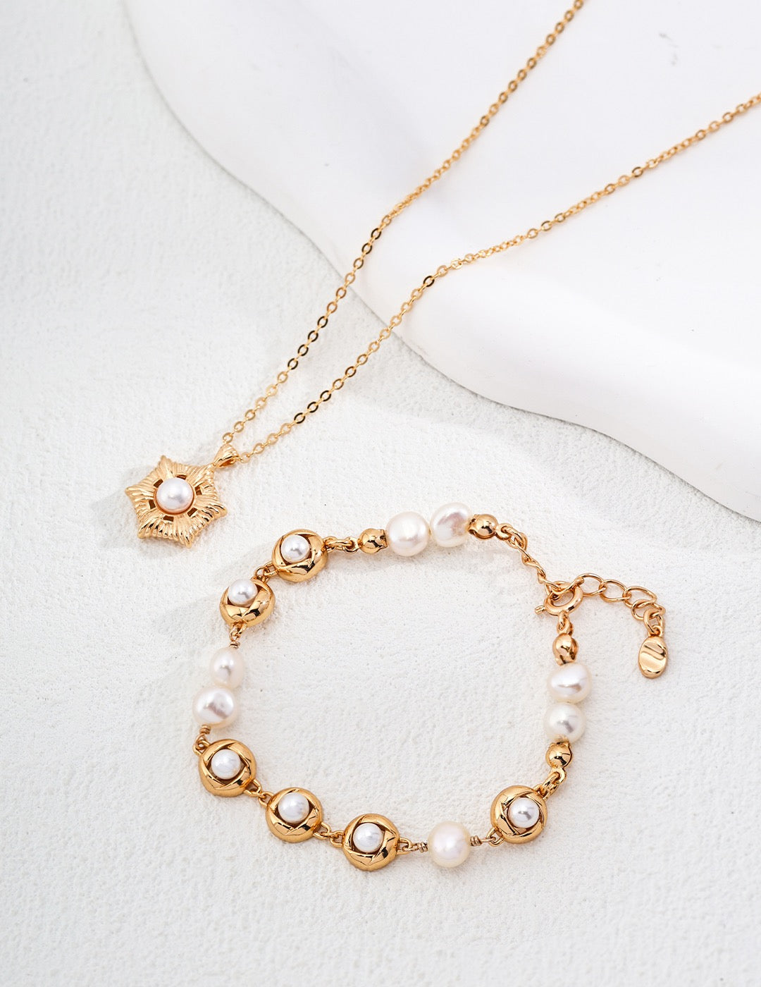 Gold necklace and bracelet set with pearls on a white background