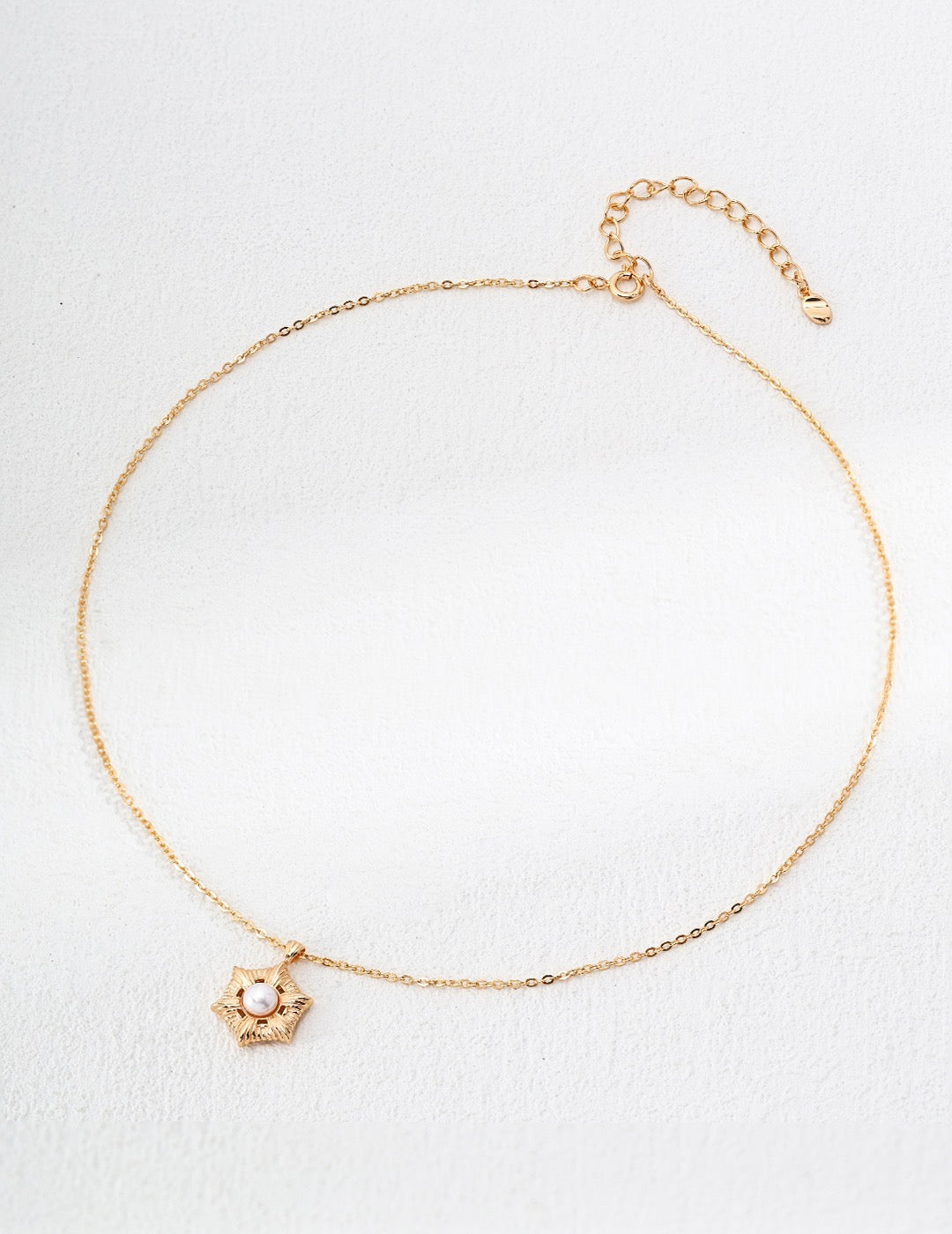 Gold bracelet with a small charm on a white background