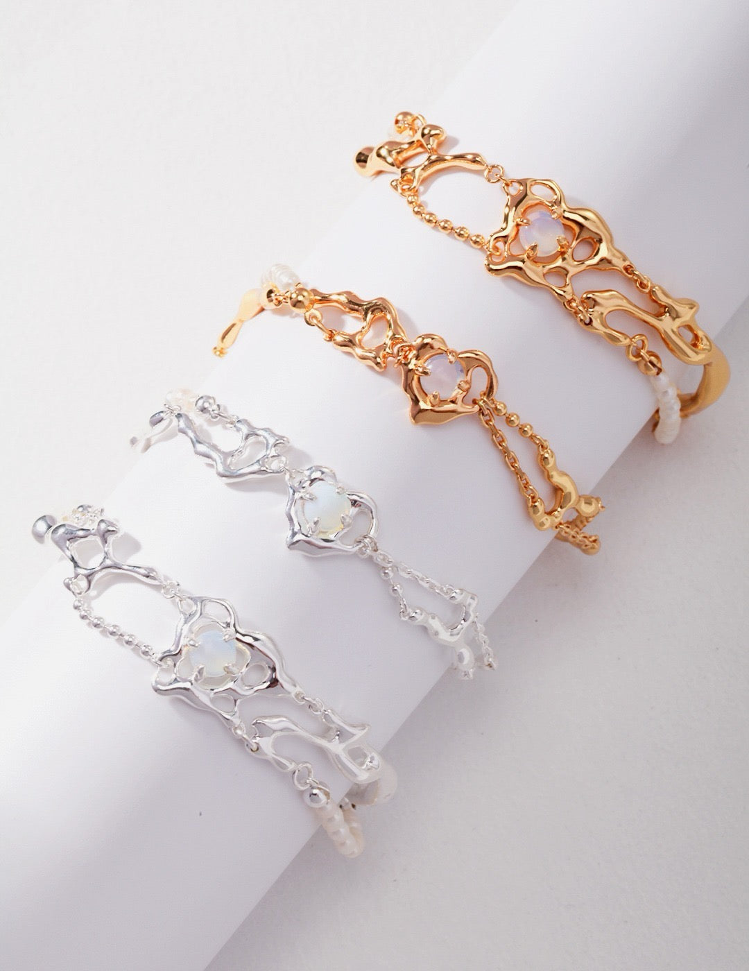 Elegant opal and freshwater pearl bracelets in gold vermeil and sterling silver with flowing, sculptural metal design, displayed on a white background.