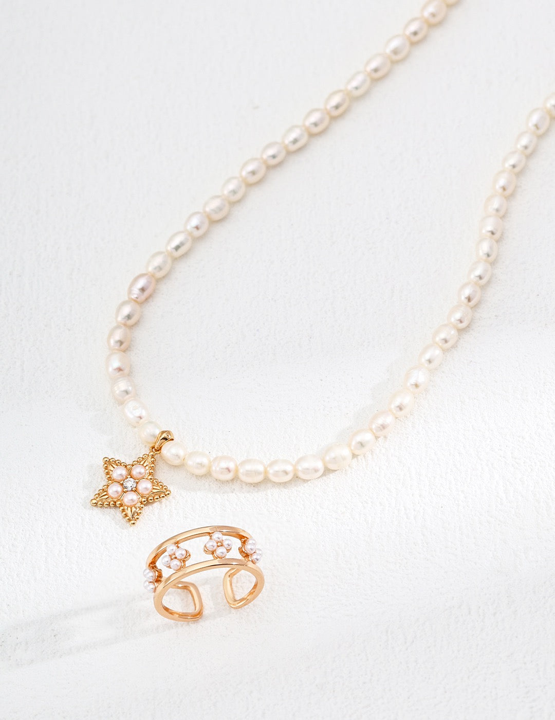 Pearl necklace with gold charms on a white background