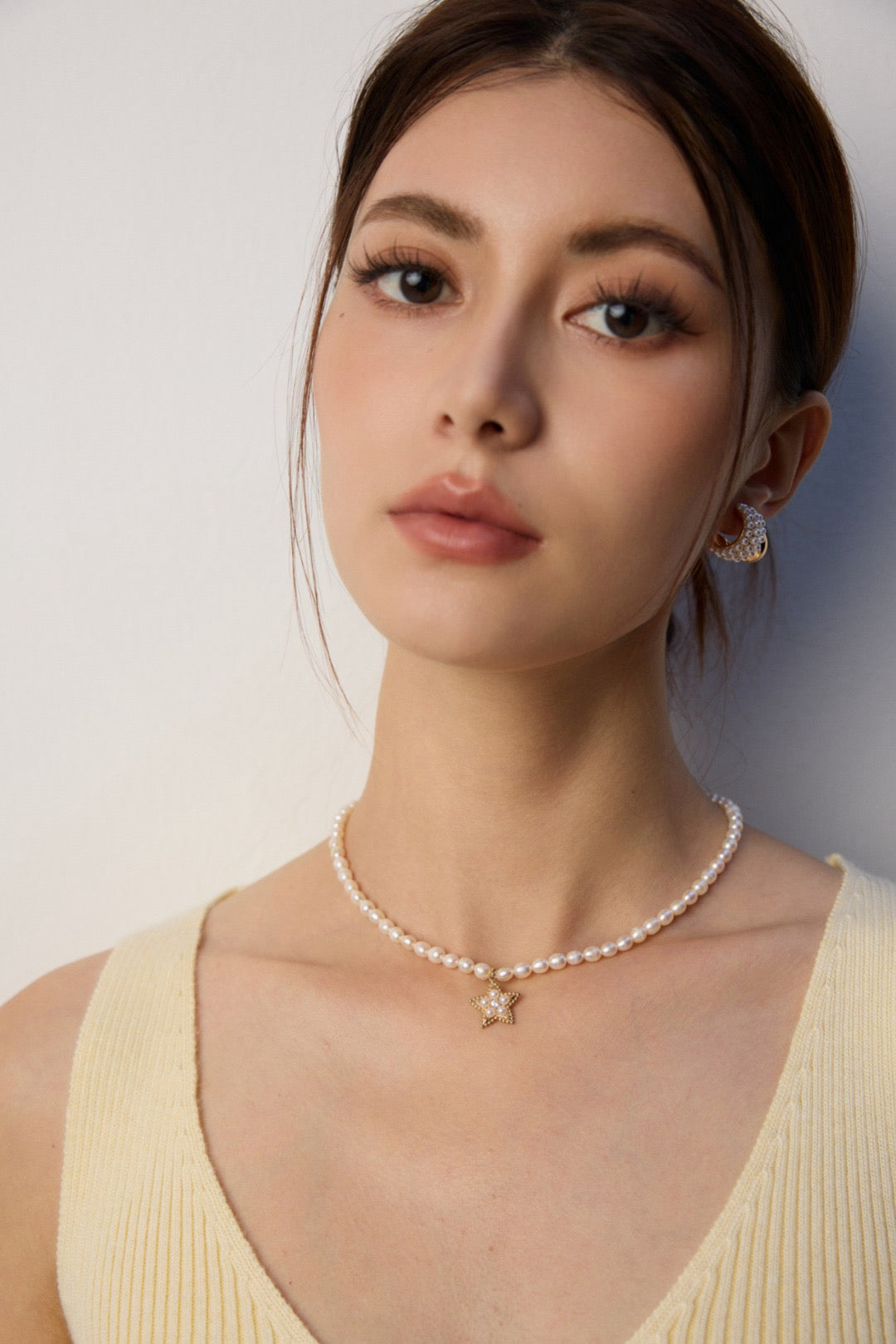 Woman wearing a pearl necklace with a neutral background