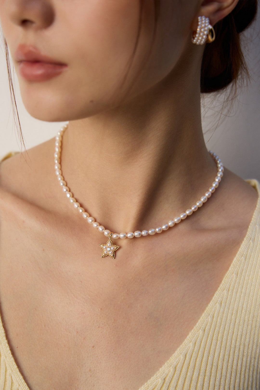Pearl necklace with a star pendant worn by a person in a neutral setting