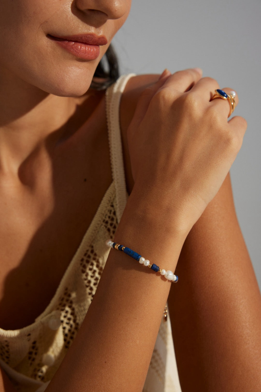 Woman wearing a bracelet with blue and white beads on a neutral background