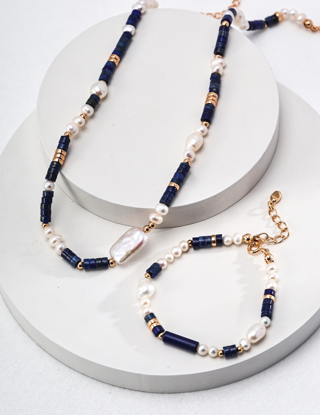 Two beaded necklaces with blue, white, and gold beads on a white surface.