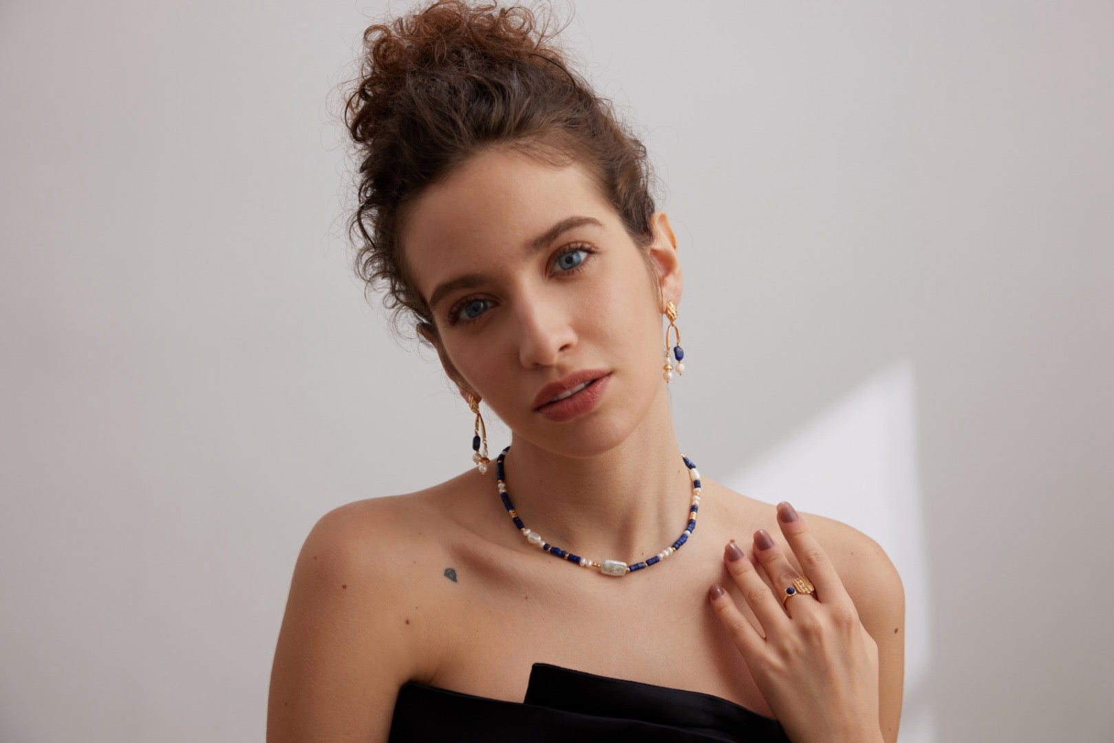 Woman wearing a necklace and earrings against a plain background