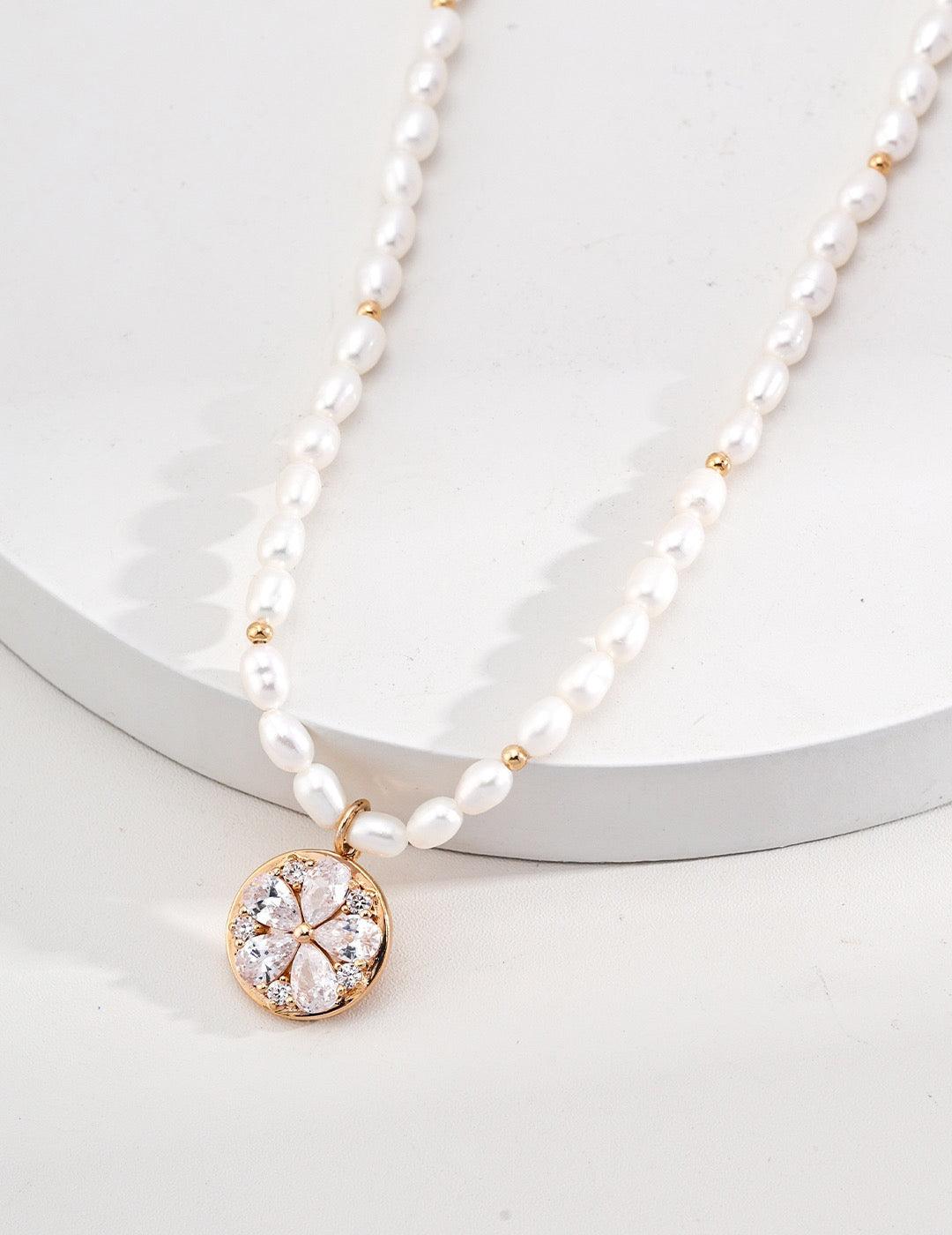 Charma Necklace displayed on the white circle stage, showcasing the zircon floral pendant detail.
