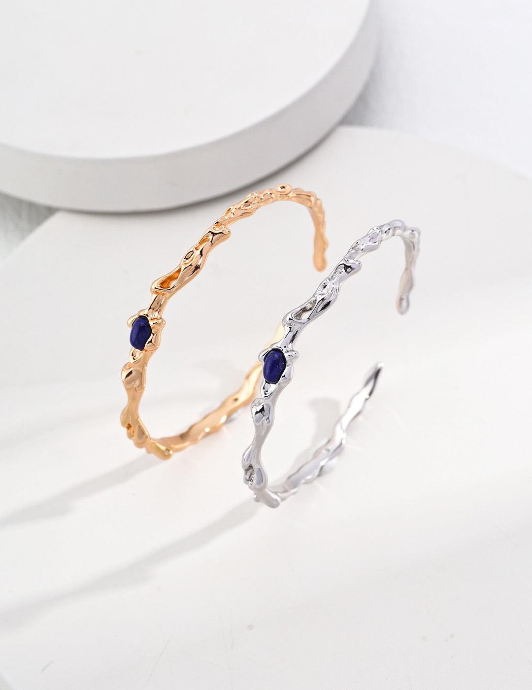 Two bracelets, one with a gold vermeil finish and one with a silver finish, both featuring a lapis lazuli centerpiece.
