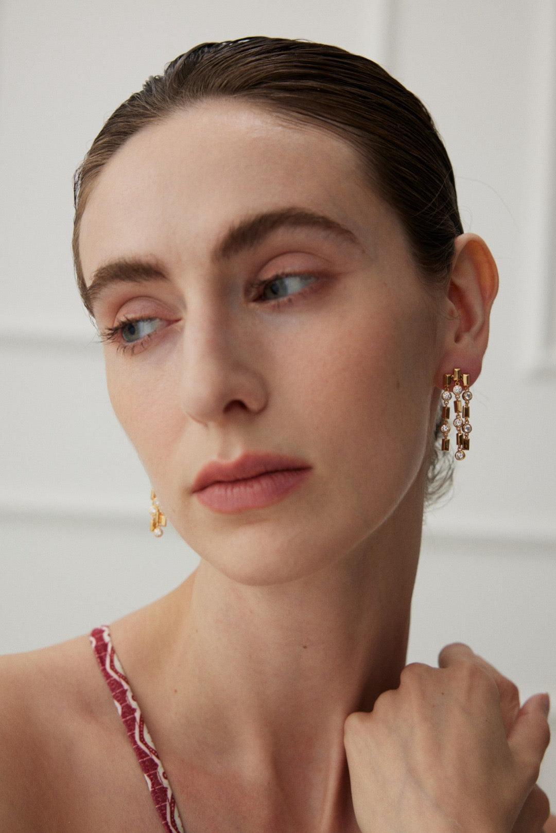 A woman wearing the Clara Tassel Earrings, which are hanging from the ear and have a tassel design with multiple drops.