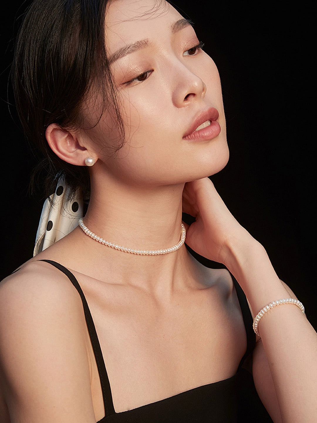 Woman wearing a pearl necklace with a black background