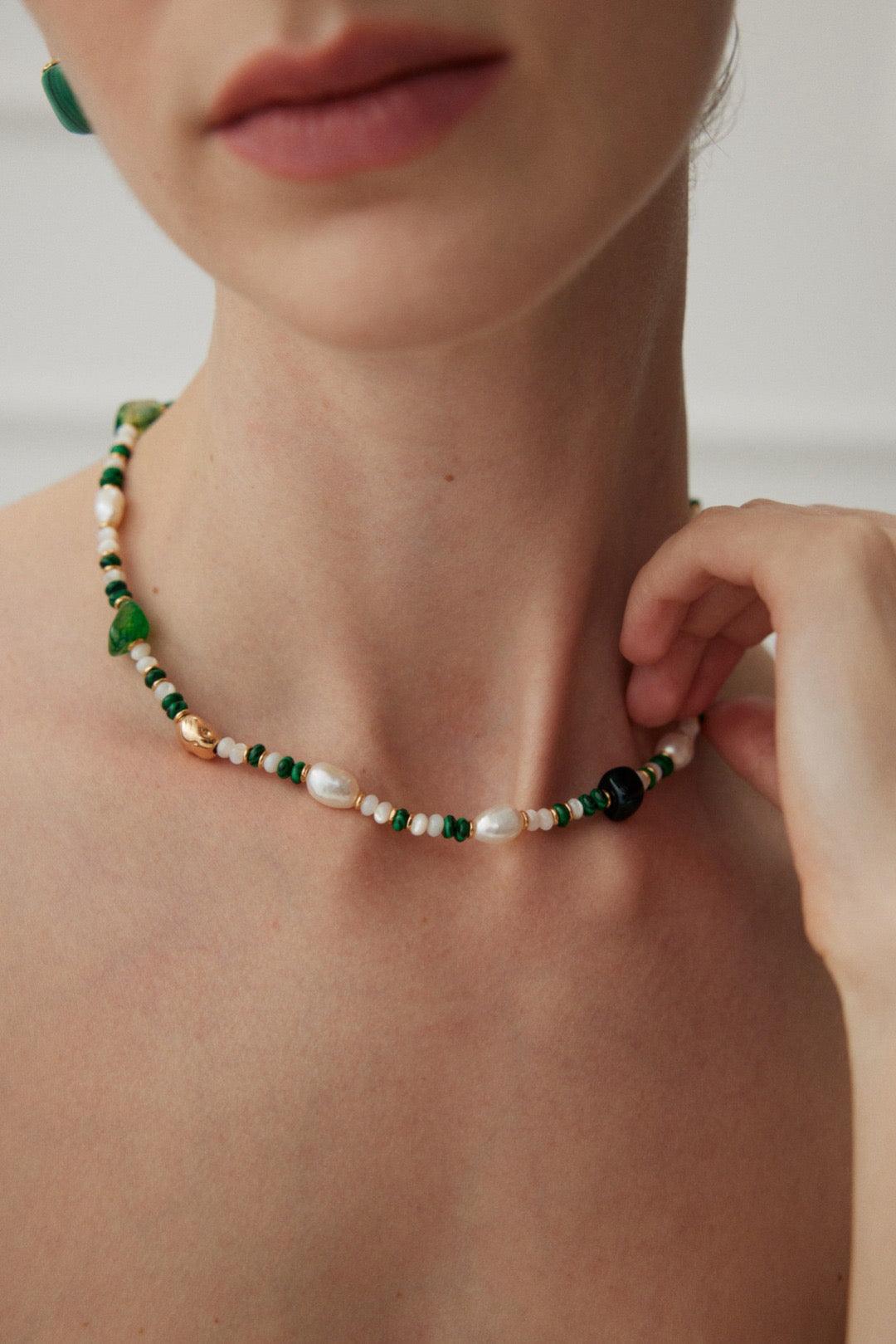 A close-up shot of the green gemstones and pearls necklace.