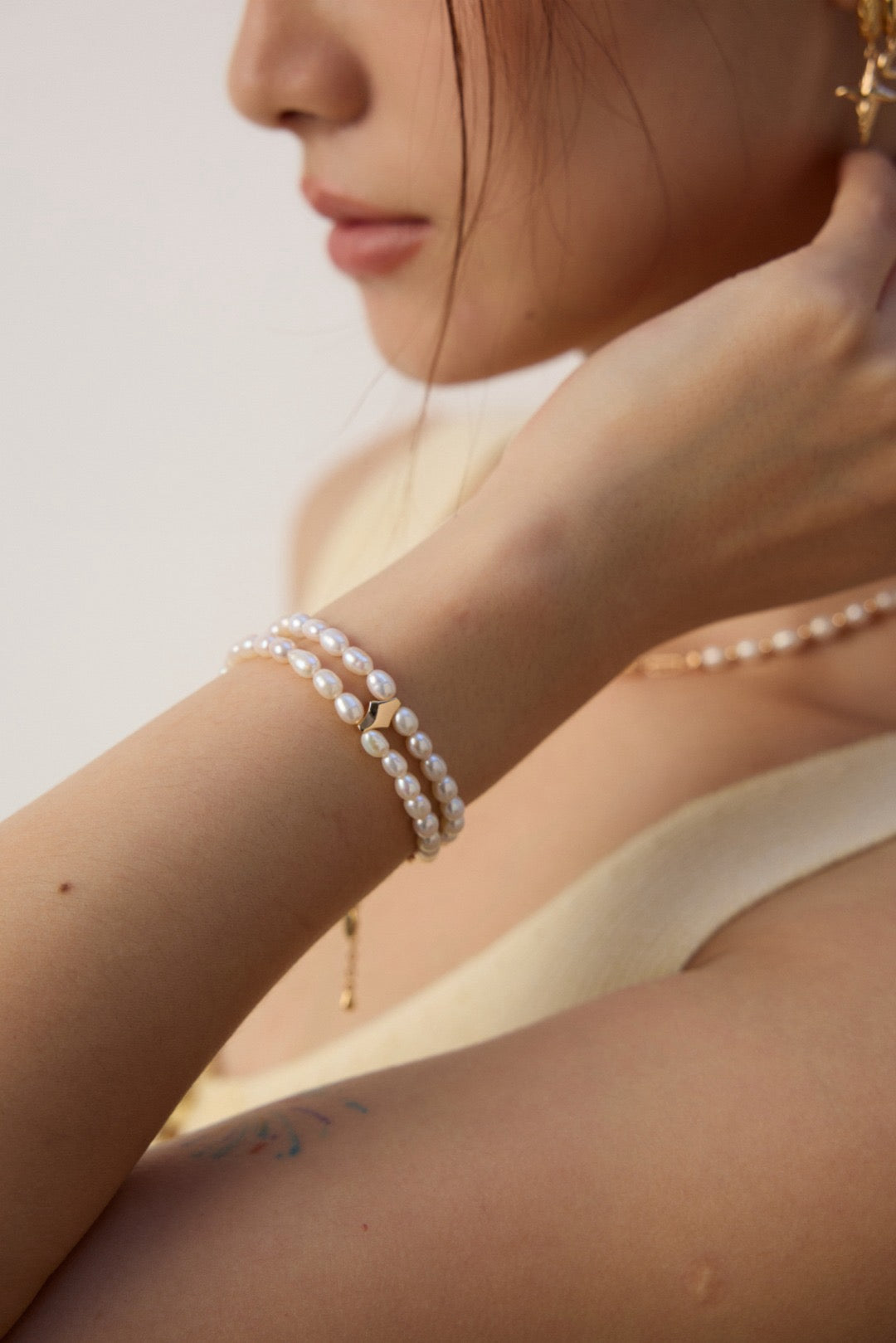 Close-up of a person wearing pearl jewelry on a plain background