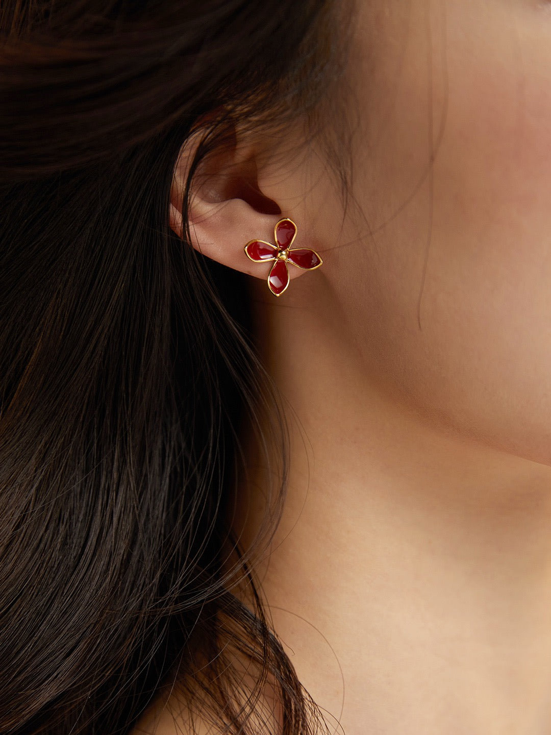 Flower-shaped earring worn by a person with dark hair.