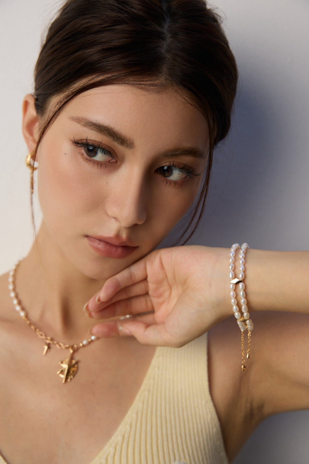 Woman wearing a necklace and bracelet with a neutral background