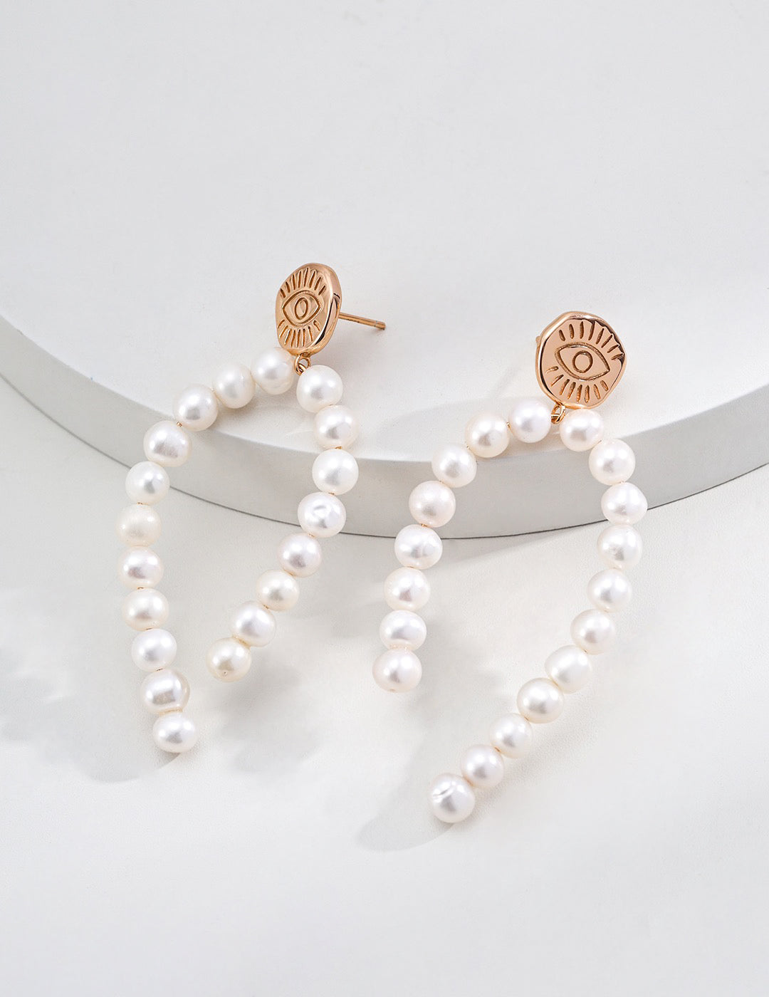 Pearl earrings with rose gold accents on a white background