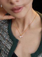 Gold necklace with a pearl pendant worn by a person