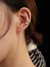 A close-up image of a woman's ear wearing a silver pearl ear cuff with two freshwater pearl inlays.