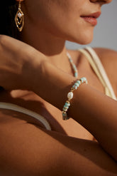 A person wearing an Edith Bracelet which is gold vermeil with pearls and a figure stone.