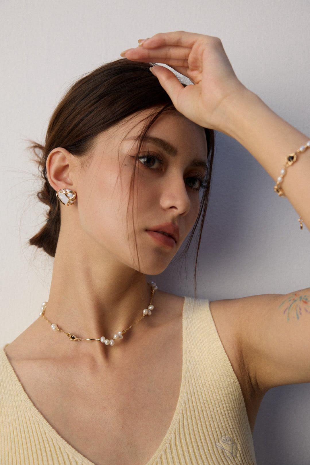 Woman wearing a necklace and earrings with a neutral background