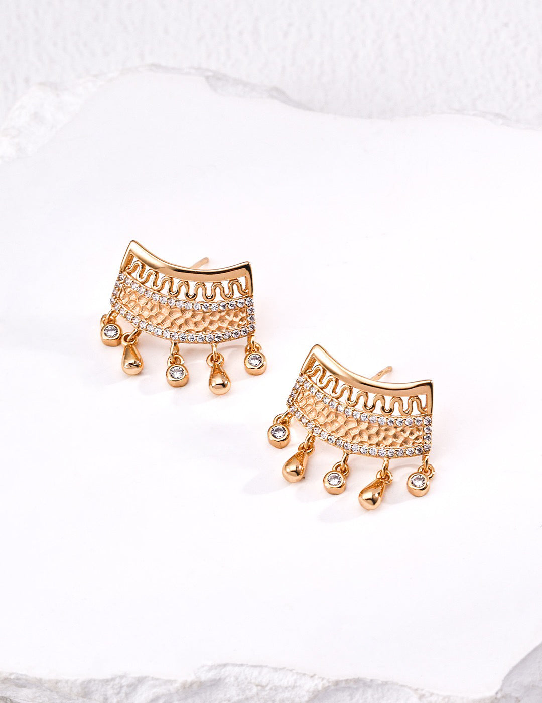 Gold earrings with intricate designs on a white background