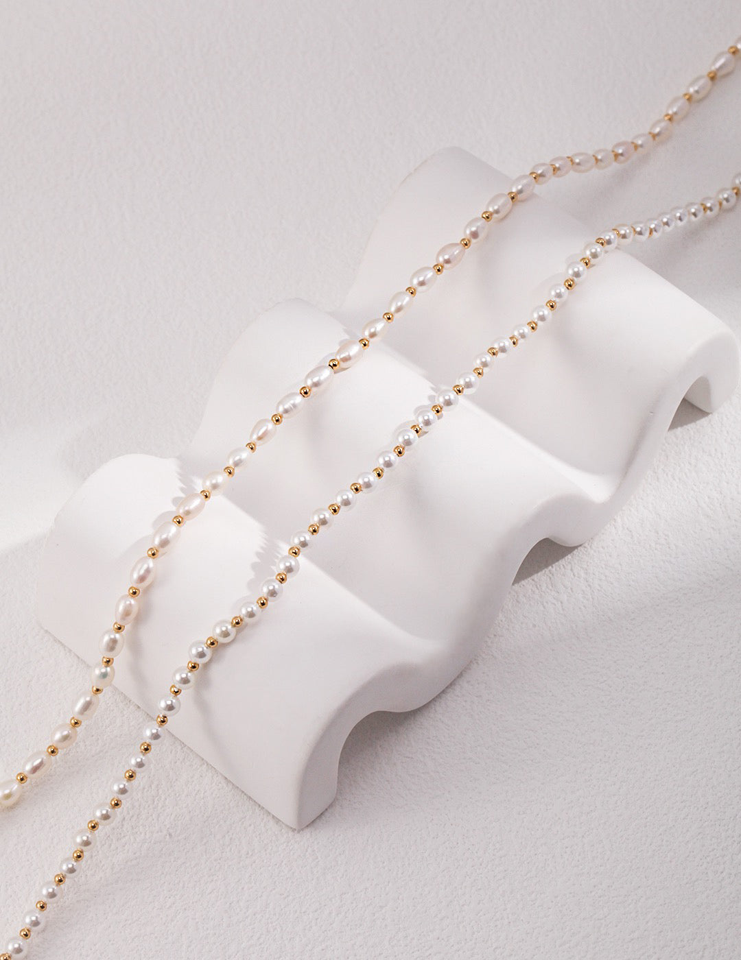Gold chain necklace on a white mannequin bust against a light gray background