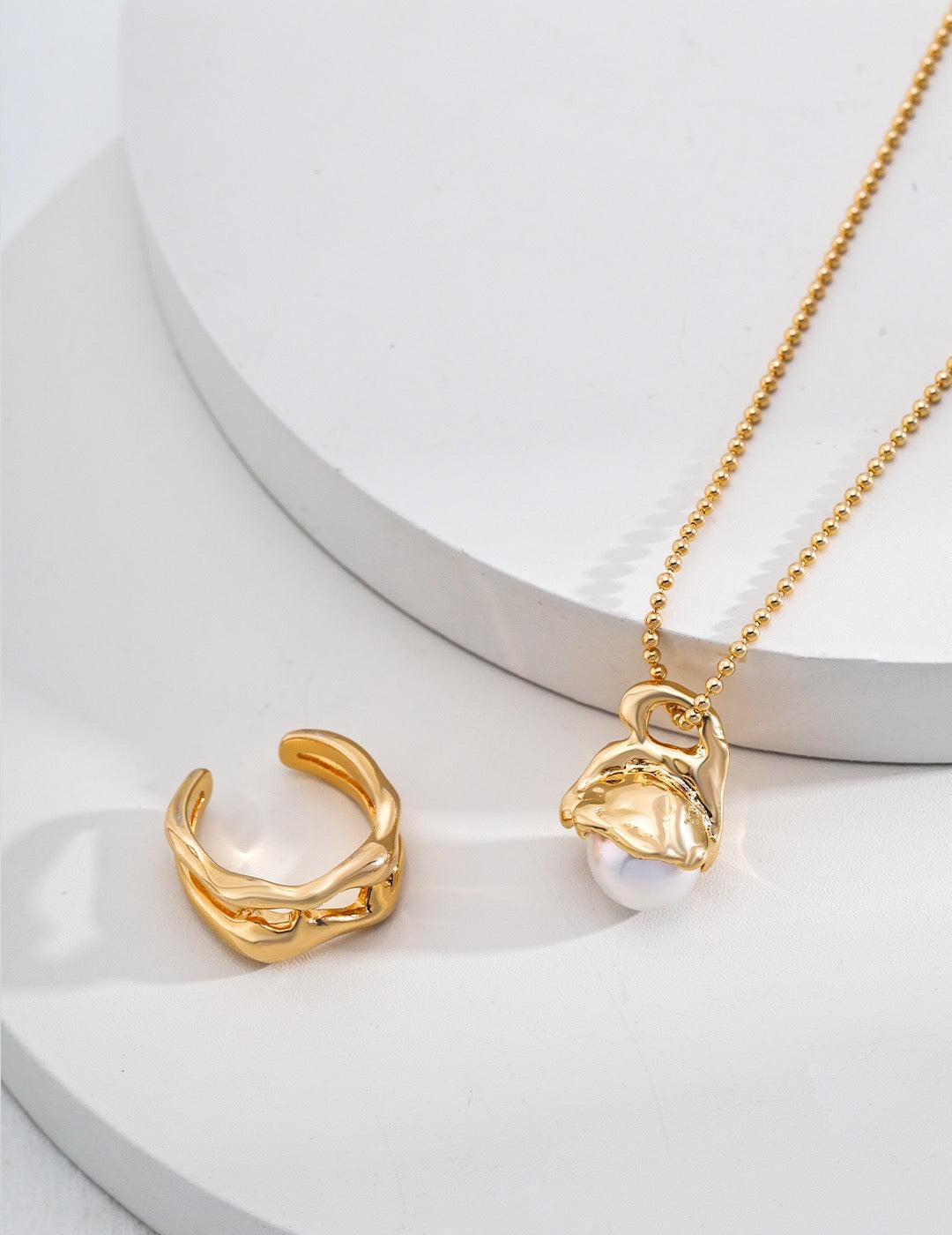Flora Pearl Pendant Necklace and a gold cuff ring displayed on the circle background.