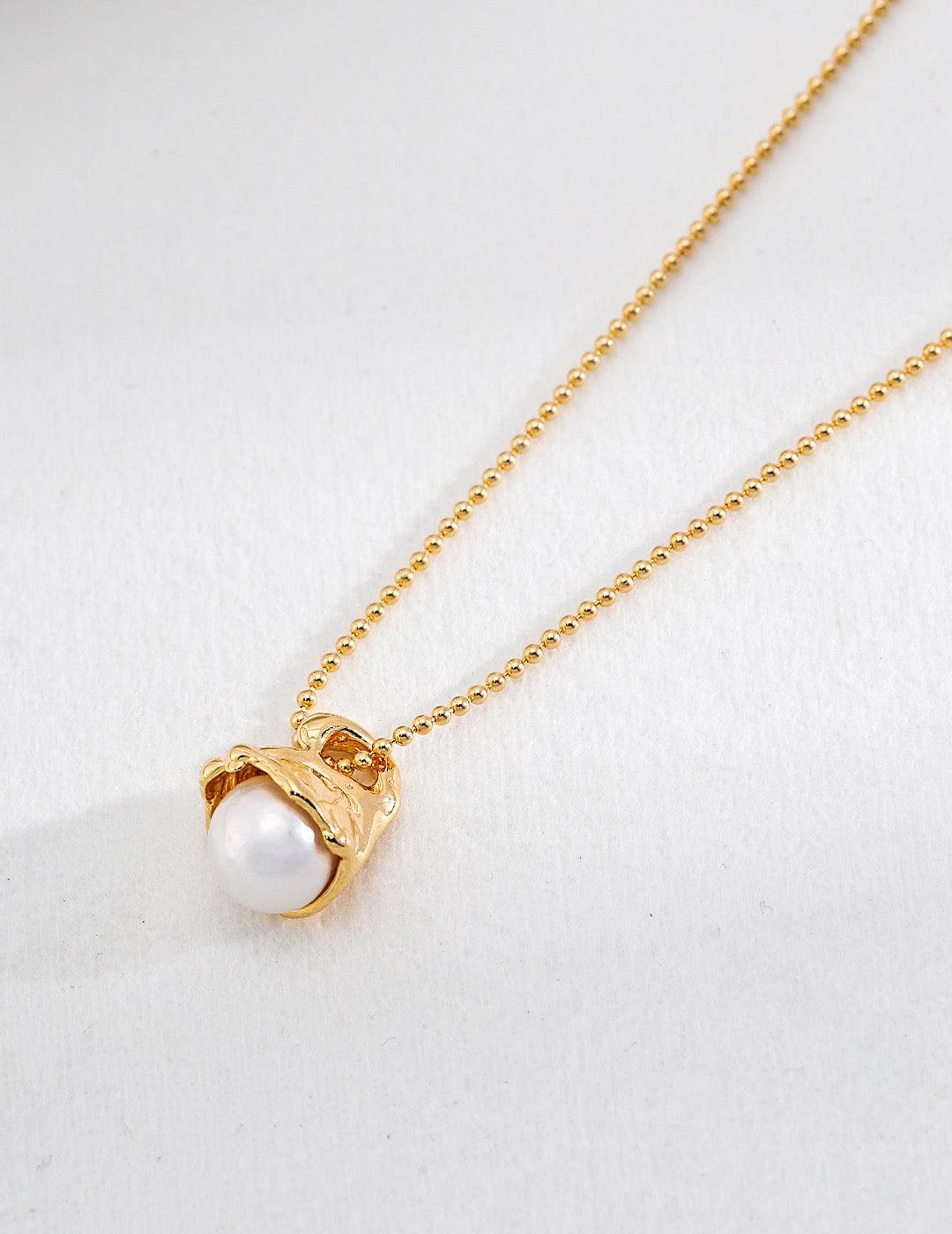 The detail of the gold pearl pendant necklace, displayed on the white background.