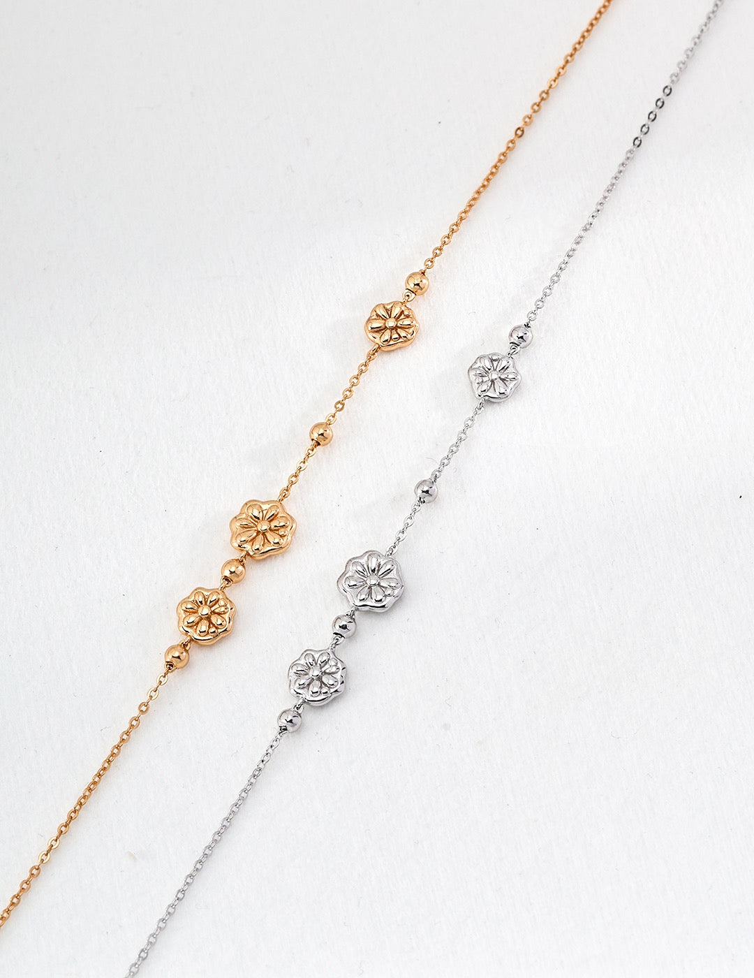 Delicate gold and silver necklace with floral charms on a fine chain.