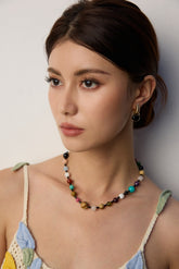Colorful round gemstone bead necklace featuring a mix of natural stones in varying hues, worn as a choker-style piece.
