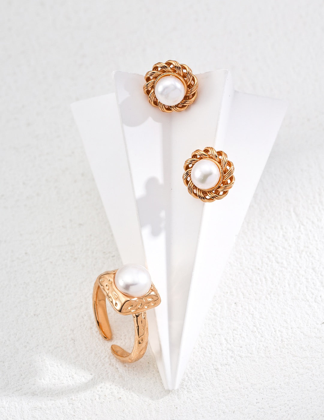 Pair of gold earrings with pearl-like centers on a white background