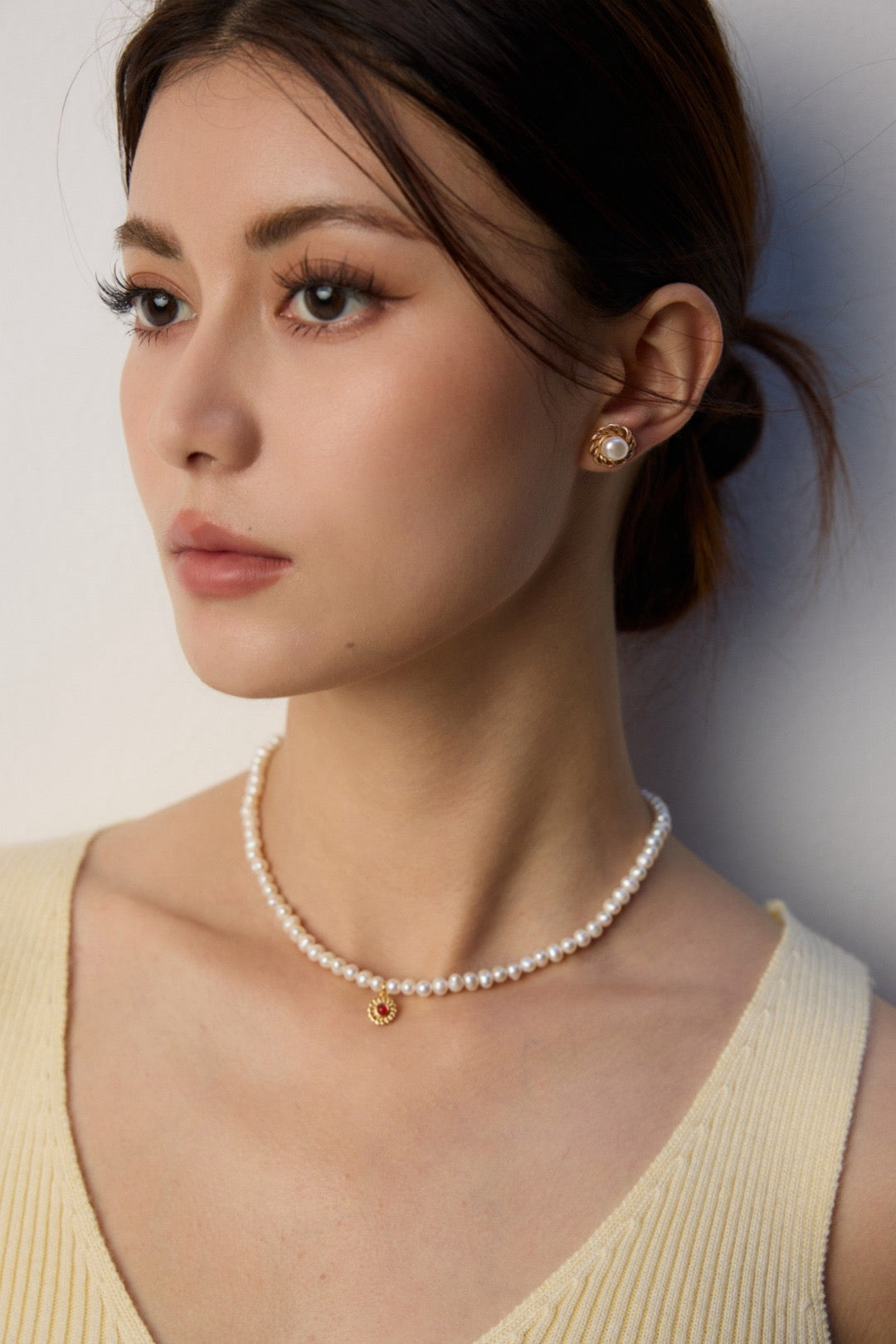 Woman wearing a pearl necklace against a plain background