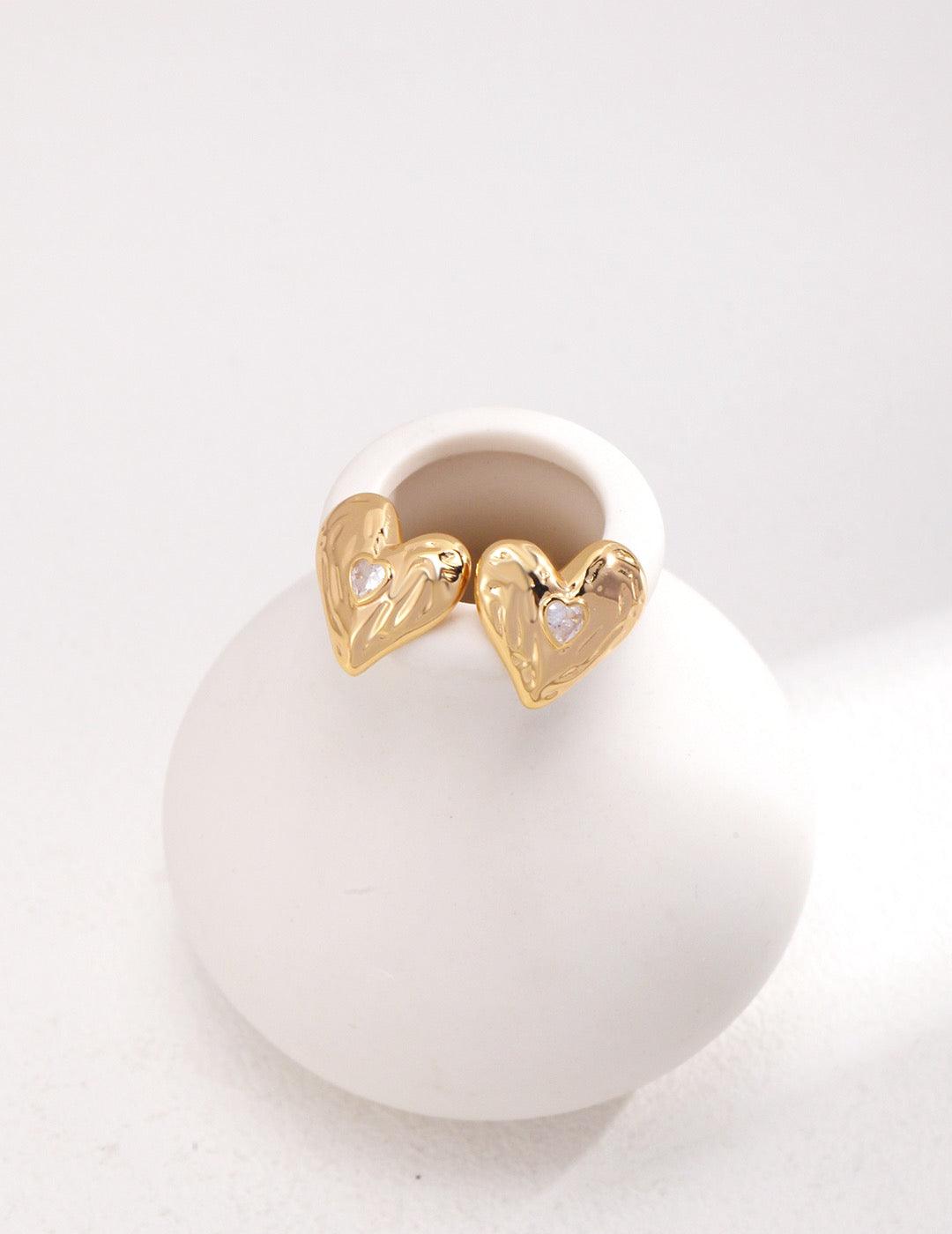 Front view of the Gold Zircon Heart Shape Stud Earrings displayed on the white vessel.
