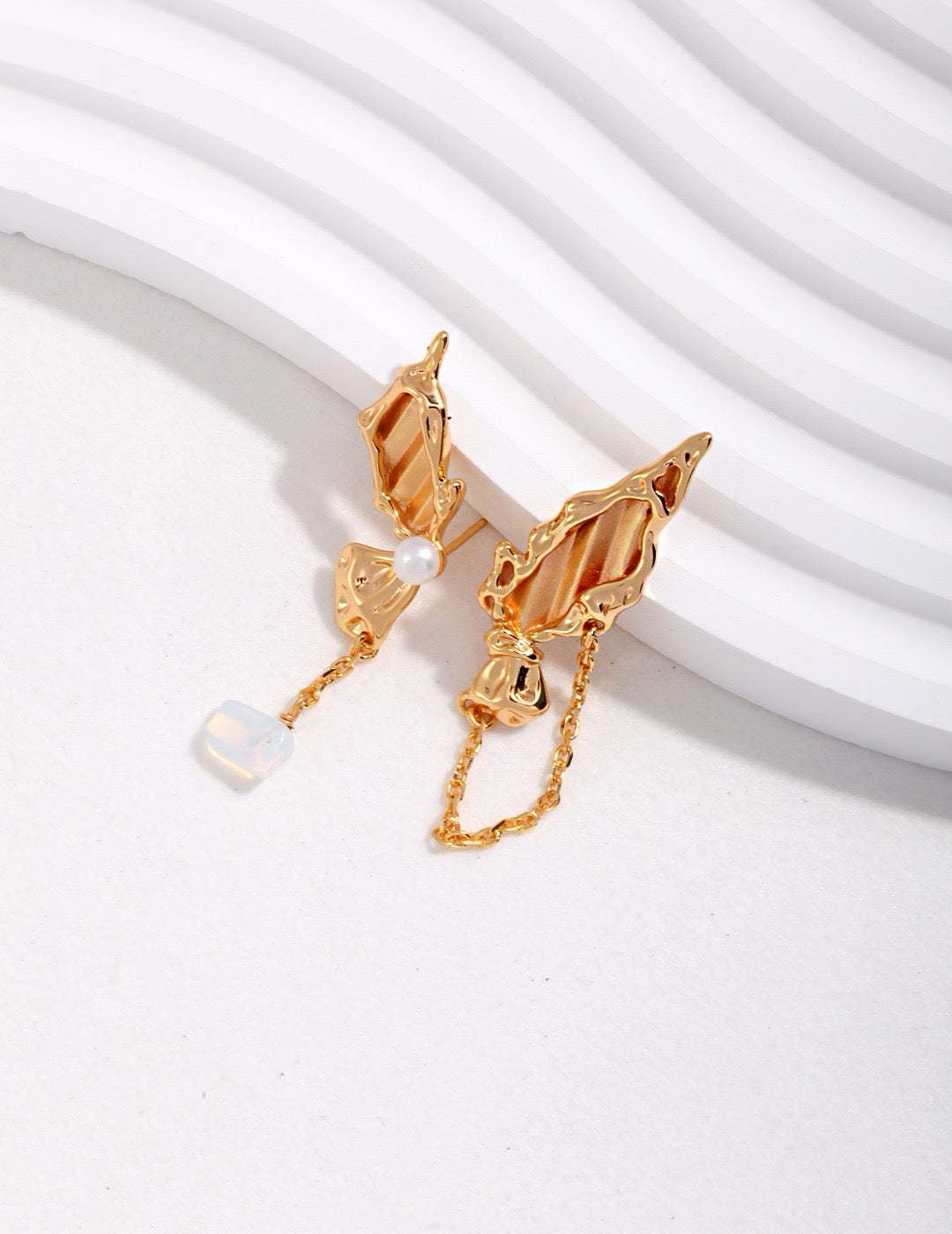 Gold butterfly asymmetrical earrings on a white background
