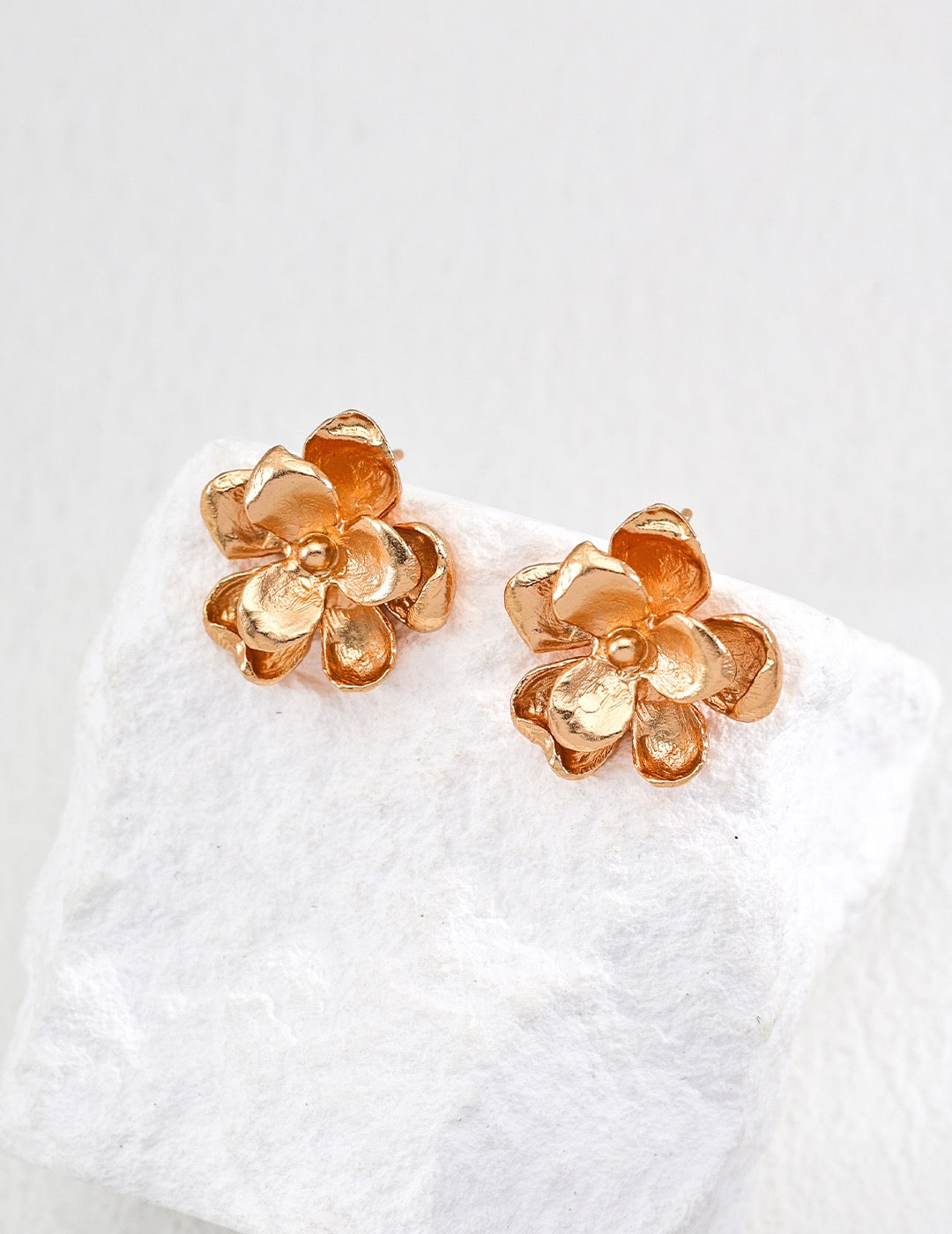 Gold flower-shaped earrings on a white background