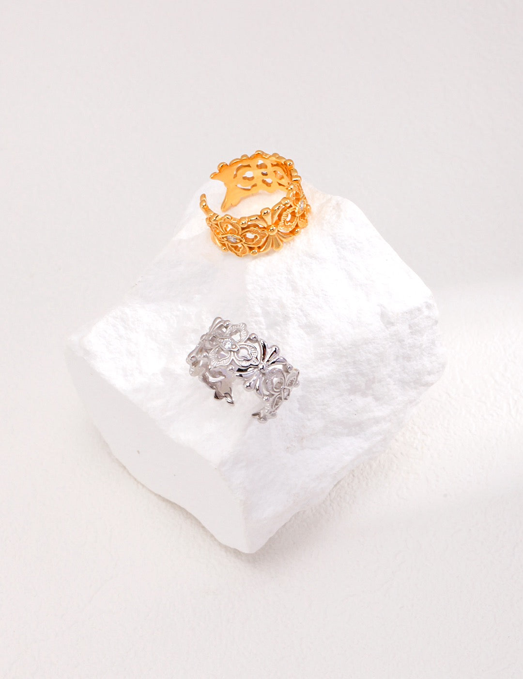 A sterling silver ring with a hollow design and a zircon inlay, displayed on a white crystal, presented on a white background.